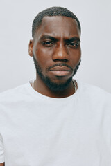Obraz premium Portrait of a serious young man with a beard wearing a plain white t shirt against a light gray background, exuding confidence and determination, perfect for diverse projects