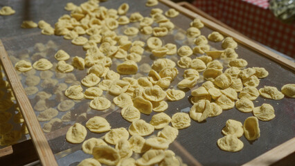 Close-up of traditional orecchiette pasta drying outdoors in bari, puglia, italy, showcasing local italian culinary artistry in a sunlit setting.
