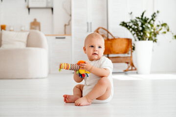 a baby is playing sitting on the floor in a bright children's room, a small child is playing with a...