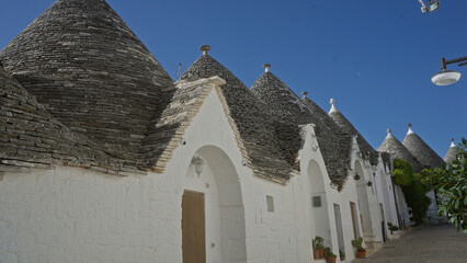 Trulli houses with conical roofs in alberobello, italy, puglia, on a sunny day, featuring ancient,...