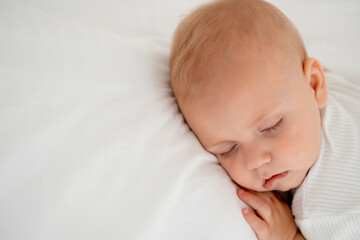 a newborn baby sleeps sweetly on his tummy, a place for text, a baby sleeps on a white bed with a pen under his cheek, a healthy baby's sleep, a close-up portrait