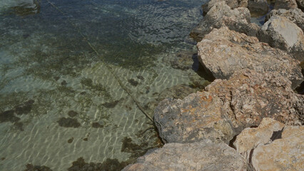 Clear, rocky shoreline with transparent water showing marine vegetation in porto cesareo, italy, puglia, salento.