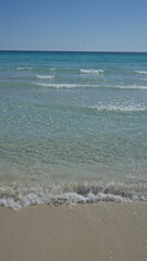 Idyllic clear water beach in porto cesareo, italy with gentle waves and sandy shore under a bright blue sky in salento, puglia.