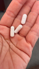 White tablets and capsules in hand. Concept of medicines, medicines and vitamins for humans. Treatment and prevention of diseases. Production of medicines, vitamins and biologically active substances.
