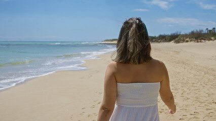 Young hispanic woman enjoying a beautiful day at pescoluse beach in salento, puglia, italy, walking along the serene shoreline amidst the stunning coastal scenery.