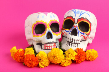 Composition with painted human skulls and beautiful marigold flowers on color background. El Dia de...
