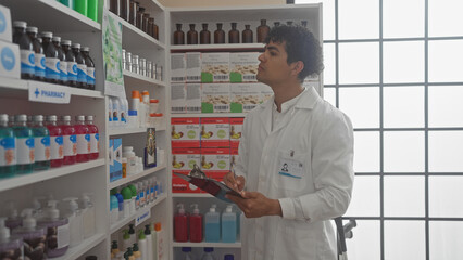 Hispanic pharmacist man inventorying medicines in a modern pharmacy