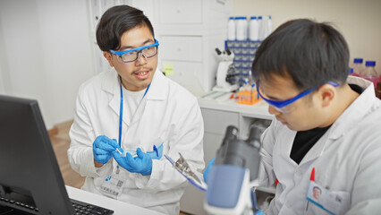 Two men in a laboratory analyzing samples with a microscope and computer.