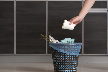 Woman throwing garbage into trash bin in kitchen
