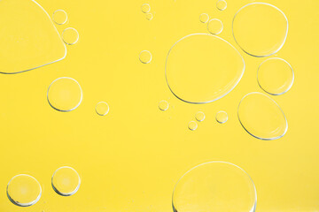 Sample of cosmetic oil on yellow background, macro view