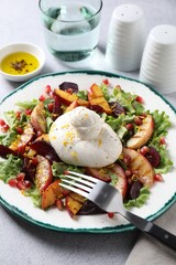 Plate with fresh burrata salad on grey textured table, closeup