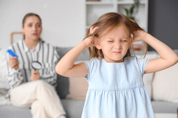 Little girl with pediculosis scratching her head at home