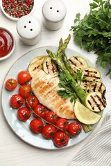 Delicious grilled vegetables and chicken breast served on white wooden table, flat lay