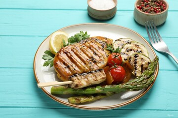 Delicious grilled vegetables and chicken breast served on light blue wooden table