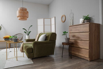 Interior of light living room with mirror, green sofa and armchair