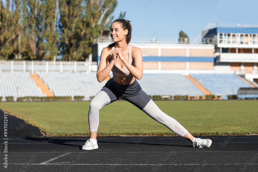 Wall mural Sporty young woman training at stadium