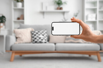 Woman with blank mobile phone in living room, closeup