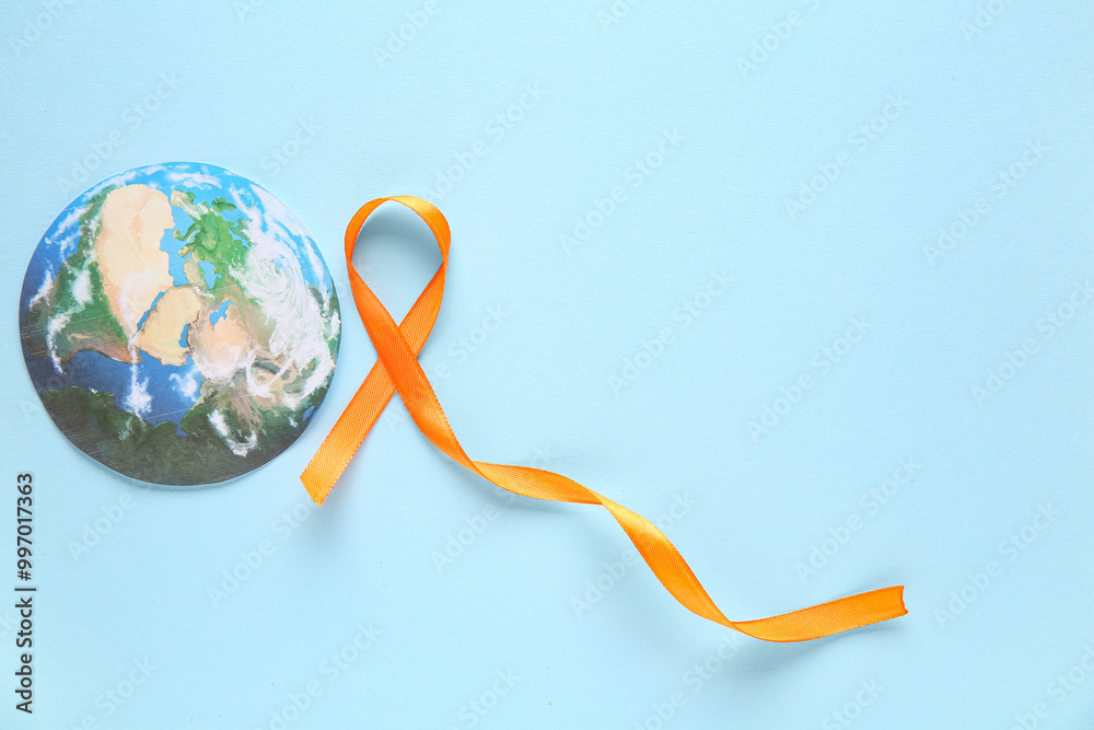 Wall mural orange ribbon and paper planet earth on blue background. world cancer day