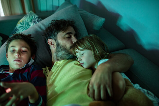 Father cuddling with children on the couch at home