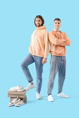 Young men in white sneakers with shoe boxes on blue background