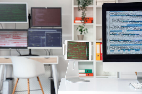 Tablet computer with code on programmer's desk in office, closeup