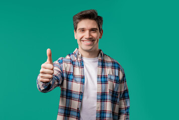 Fototapeta premium Positive smiling man with hand sign like, thumb up gesture.Happy hipster on blue