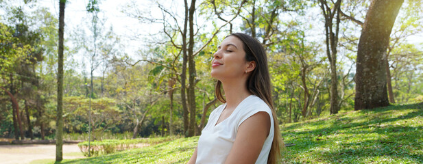 Relaxed young woman breathing fresh air in a city park. Panoramic banner view.