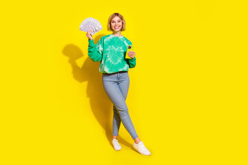 Full length photo of adorable lovely girl wear tie dye sweatshirt winning cash modern device empty space isolated yellow color background