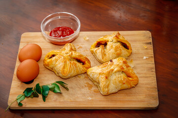 Kerala Style Tasty Egg Puffs with Tomato Sauce, Curry Leaves and Egg On Chopping Board