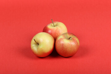 Three Fresh Red and Yellow Apples on Vibrant Red Background – Isolated, Healthy Fruit, and Nutrition Concept