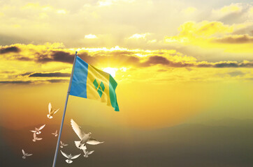 Saint Vincent flag waving with flying doves against sunset or sunrise. Saint Vincent flag for...