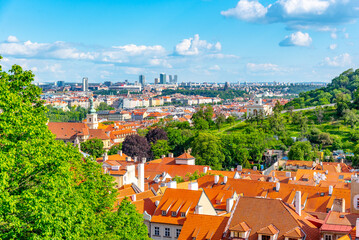 Naklejka premium A vibrant view of Prague Lesser Town, with its iconic red rooftops and lush greenery, under a clear blue sky. Prague, Czechia