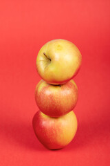 Three Fresh Red and Yellow Apples on Vibrant Red Background – Isolated, Healthy Fruit, and Nutrition Concept