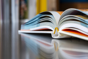 Close-up opened hardcover book with reflection on metal desk