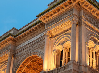 Obraz premium Top of the entrance to the Galleria Vittorio Emanuele II in Milan, with artificial lighting, on a summer evening at the golden hour just before sunset with blue sky