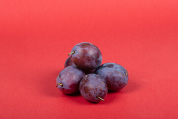 Fresh Purple Plums on Red Background – Isolated Juicy Fruits Perfect for Healthy Eating and Food Photography