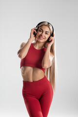 Young caucasian woman wearing headphones dancing active isolated on gray wall listening to music laughing cheerful