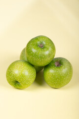 Fresh Green Apples: Trio of Crisp Granny Smith Fruits on Pale Yellow Background - Healthy Snack, Organic Produce, and Natural Vitality in Minimalist Setting