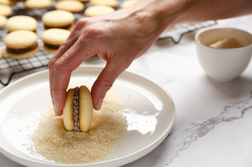Putting coconut in a cornstarch alfajor. 