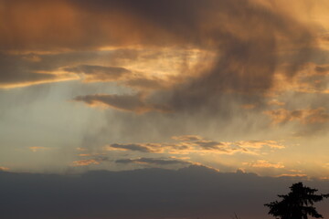 close-up swirls of rain fall from storm clouds at sunset