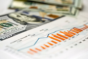 Stack of dollar bills and a graph with orange bars. The graph shows the value of the dollar over time