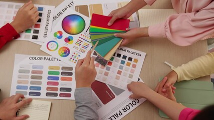 Top view slow motion hand closeup on table of two designer choose color for graphic design working or client seeking color application at creative chromatic consultation from designer. Variegated