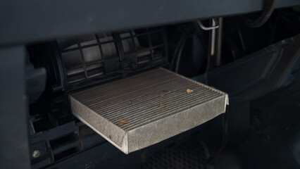 A mechanic changes the cabin air filter of a car. Dirty car cabin air filter. Timely car service. 