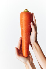Person holding a carrot on a white background, with hands at each end of the carrot
