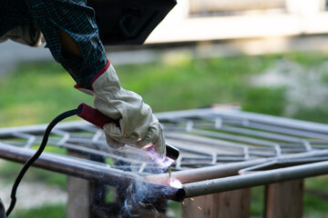 Close up of a welder welding metal frame outdoors