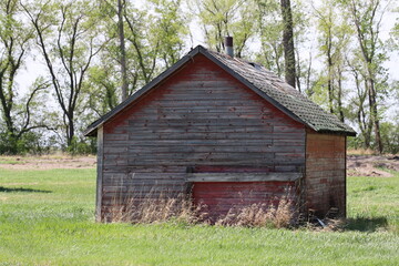 dilapidated abandoned wooden farm building with faded classic red paint