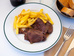 Spanish Secreto de cerdo - fried pork in red, served with french fries