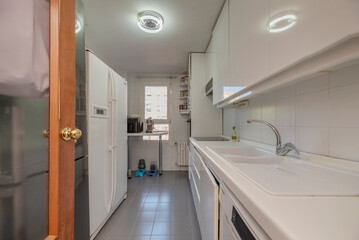 Kitchen furnished with white cabinets, countertops, double refrigerator and grey tiled floors