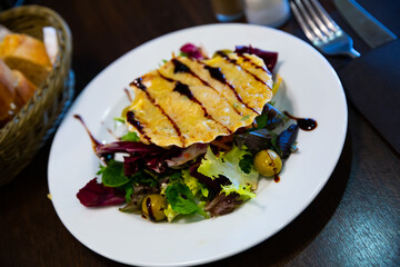 Close up of scallop snack baked with cheese served on seashell, garnish from lettuce and balsamic