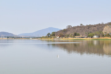 Fototapeta premium A view of Valencia dam with a small town in the background. The water is still and the sky is clear, Jalisco Mexico